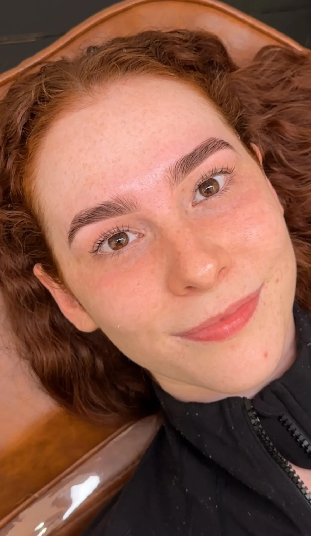Client with finished brow styling — defined arch, warm indoor light