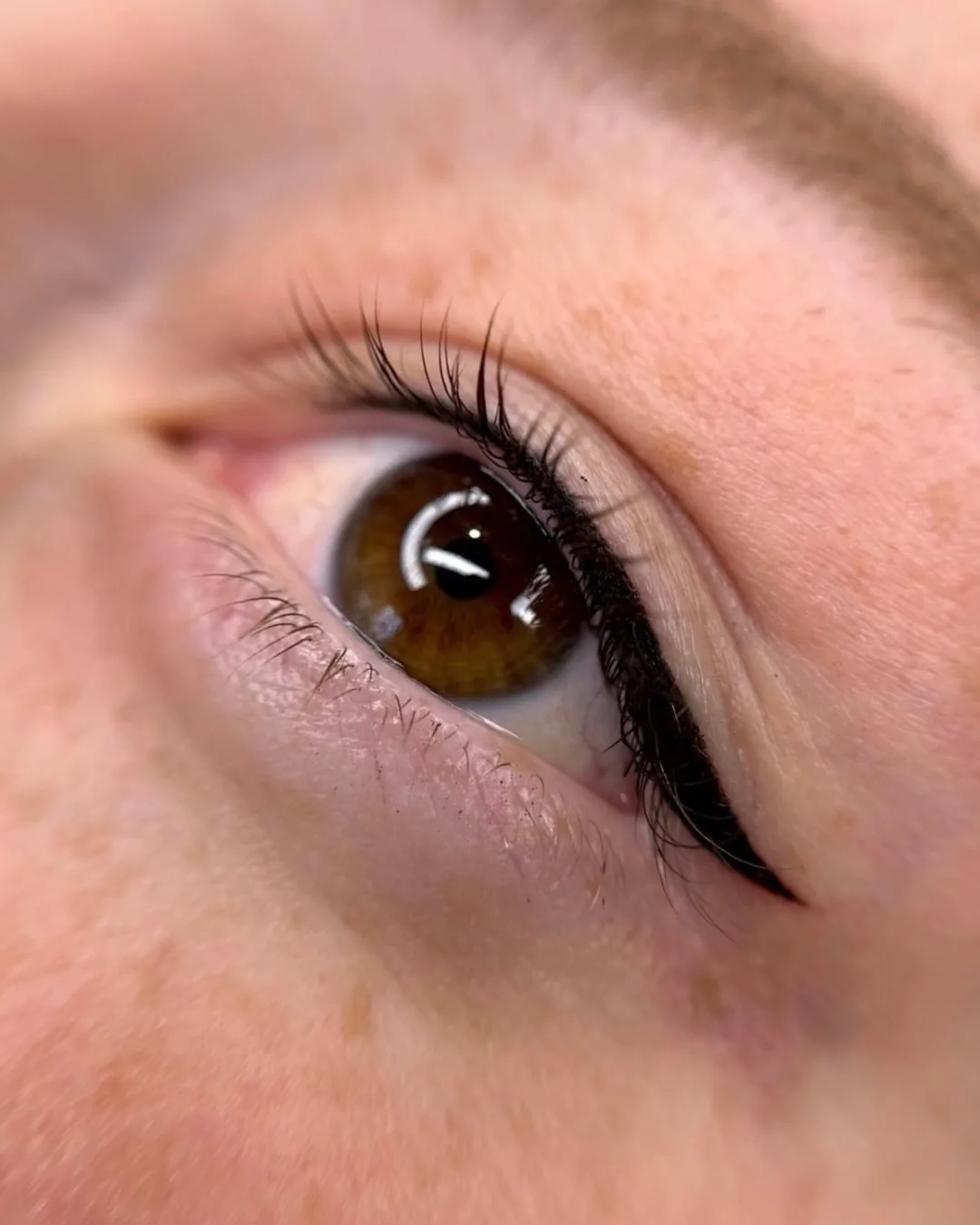 Close-up of an open eye with a healed winged eyeliner cosmetic tattoo