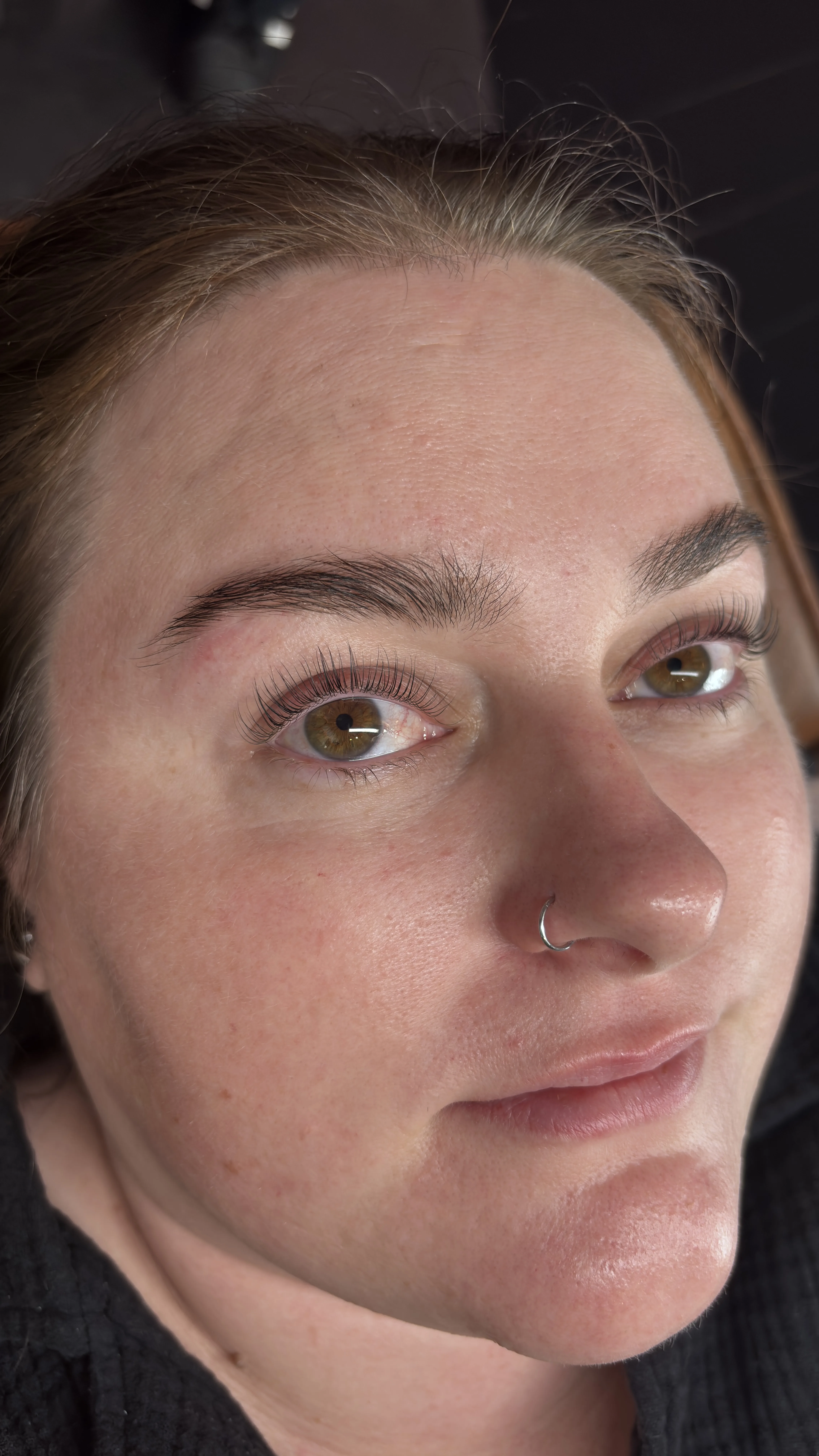 Client selfie showing softly shaped natural brows — cosmetic brow tattoo result